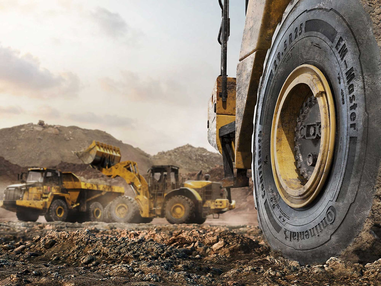 Pneu Continental OTR (A imagem retrata um cenário de mineradora. Em primeiro plano, vemos o pneu Continental OTR de uma máquina grande, com características robustas, sugerindo um ambiente de trabalho intenso e extremo. O pneu é negro com detalhes em amarelo, indicando a marca Continental. A parte de trás mostra três máquinas pesadas, como carregadeiras e caminhões, que estão trabalhando em um terreno irregular e acidentado. O solo é de terra, com algumas pedras visíveis e uma coloração marrom, indicando que o local está sendo escavado ou nivelado. O céu ao fundo é levemente nublado, com tons claros de azul e cinza, e a atmosfera sugere um dia de trabalho ativo, com poeira no ar, proveniente do movimento das máquinas. A cena transmite uma sensação de grandeza e atividade industrial)