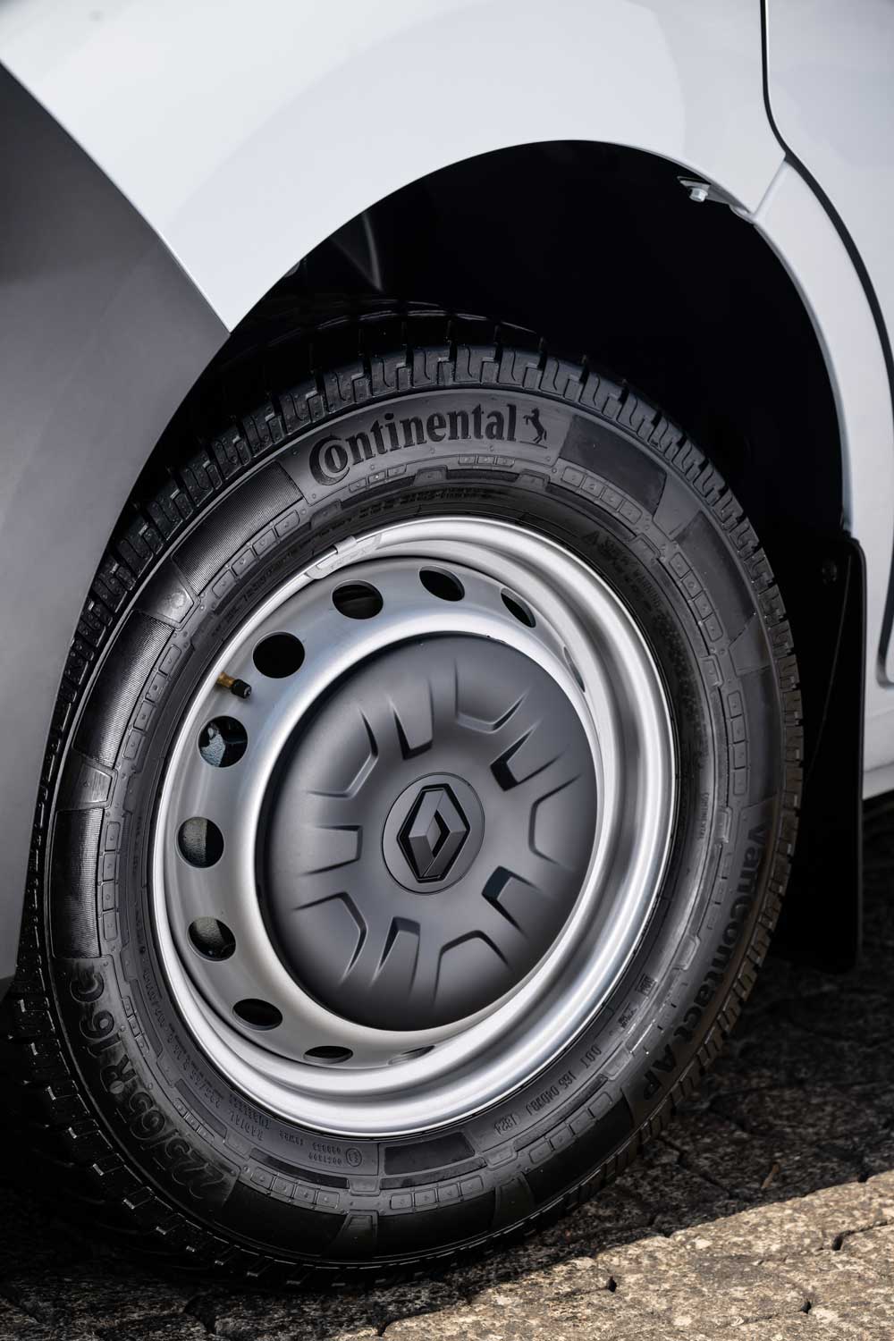 (A imagem apresenta um close-up detalhado do **pneu original da Renault Master**, modelo VanContact AP na medida 225/65R16C 112/110R da marca Continental. Este pneu exibe o nome da marca claramente gravado na lateral, acompanhado de sulcos profundos, projetados para oferecer uma excelente aderência em diversos tipos de terreno. A roda possui uma calota metálica, com o emblema da Renault no centro de uma calota, destacando a originalidade da peça e garantindo uma estética uniforme e funcional para o veículo.  Os pneus originais da Renault Master são projetados para suportar o peso e as exigências do transporte de carga, oferecendo durabilidade, segurança e performance em estradas urbanas e rodoviárias. A combinação entre a marca Continental e a engenharia da Renault assegura que o veículo entregue eficiência em consumo de combustível e menor desgaste, mesmo em usos intensivos.  Com esse enfoque, a importância de utilizar o pneu original da Renault Master é reforçada, sendo ele essencial para garantir o desempenho ideal do veículo, evitando problemas de segurança e mantendo a integridade da mecânica da van)